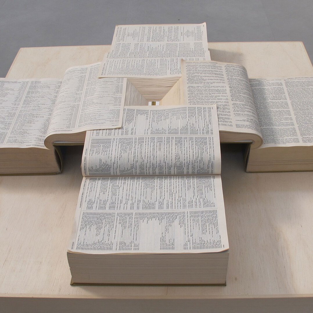 quattro libri giuridici con pagine intersecate fra loro che formano una piramide inversa